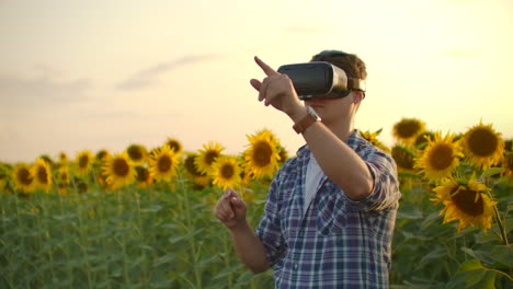 A-man-works-with-augmented-reality-glasses-on-the-field-with-sunflowers.-These-are-modern-technologies.